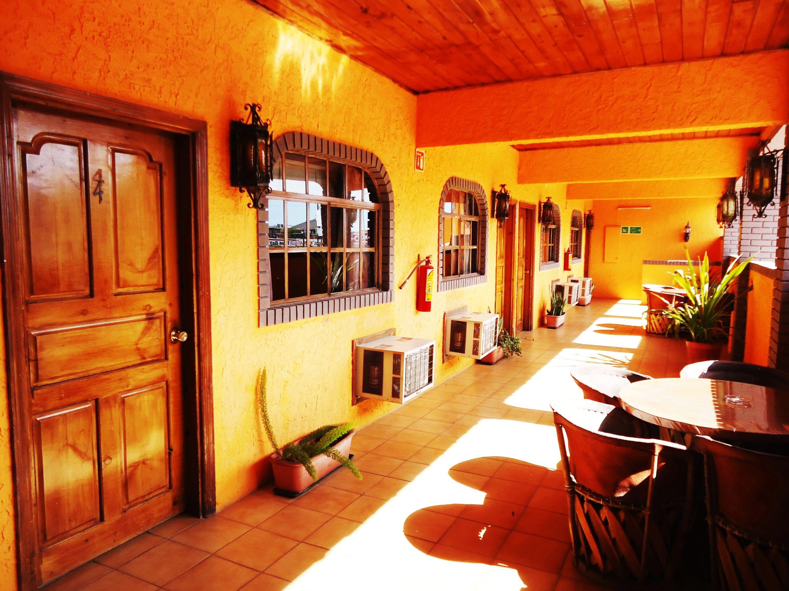 Sunlit hotel corridor with wooden doors and terracotta tiles